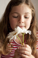 Obraz na płótnie Canvas little girl smelling daisies