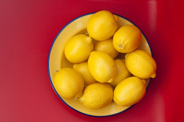 bowl of lemons against red background