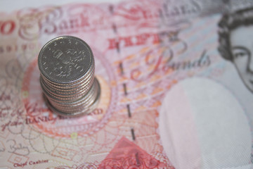 five pences stacked on a fifty pound note