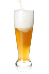 White beer is pouring into a glass from bottle