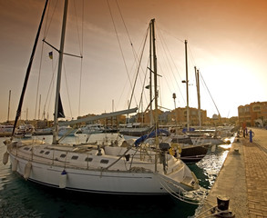 Sailing yachts in a marina at sunset