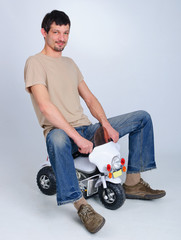 Adult handsome guy playing children's games on a motorcycle