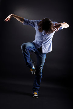 young man modern dancer in action against black