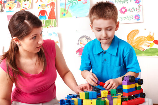 Child and teacher with construction set in play room.