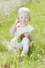 little girl with cherries sitting on grass