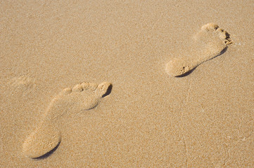 Fototapeta na wymiar Pair of footprints on a sandy beach background