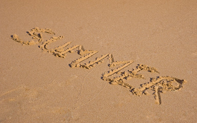 Summer writing on a sandy beach background