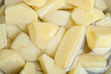 Closeup of potatoes cut in pieces in water with selective focus