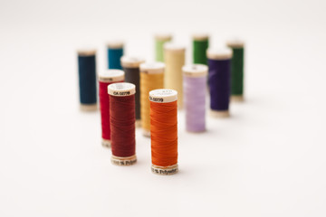 Colored thread bobbin, mins and meter on white background