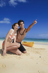 young couple on the beach in hawaii pointing