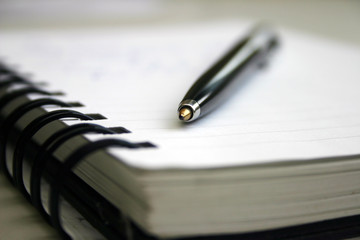 A notebook and black pen in blur background.