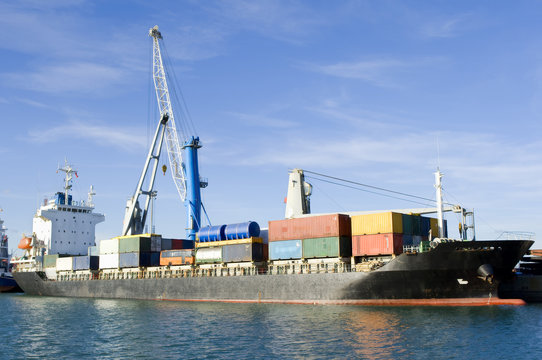 barco siendo cargado contenedores con grua en el puerto