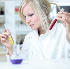 Closeup of a female researcher holding up a test tube and a reto