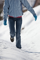 pretty young woman walking in deep snow on a sunny winter day