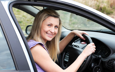 Fototapeta na wymiar Happy female driver at the wheel sitting in her car