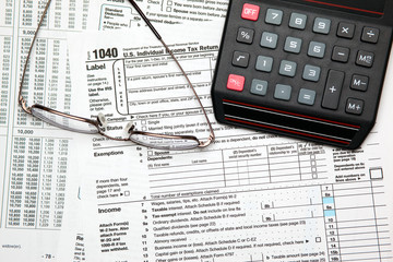Tax time - Closeup of U.S. 1040 tax return with calculator and g