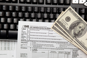 Tax time - Closeup of U.S. 1040 tax return with $100 bills and c