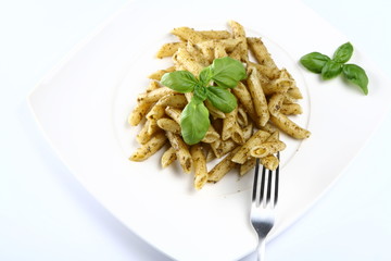 Penne with pesto decorated with basil and a fork