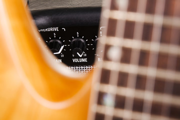 Electric guitar with amplifier, focus on volume knob
