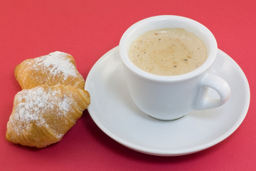 Cup of coffee with croissants on a red background