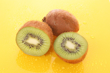 Obraz premium Wet kiwi on yellow background