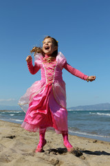 Girl dressed as a princess showing her happiness on a beach