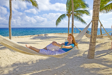 Obraz na płótnie Canvas Young woman in hammock on background of palm trees and ocean..