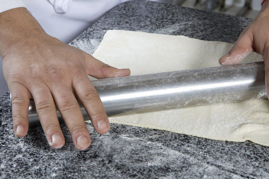 man`s hands to roll out dough