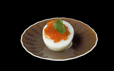 Snack from egg and red caviar on a plate