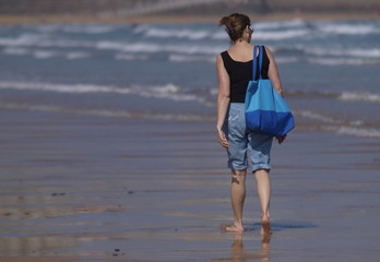 Mujer con bolso paseando por la playa