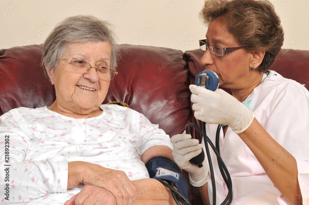 Wall mural Mixed raced nurse measuring senior patient's blood pressure