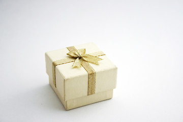A white gift box or jewelry box with gold ribbon bowknot.