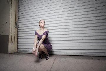 Woman squatting in a dark urban setting