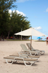 reclining chairs under the shade of beach umbrella