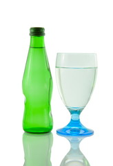 Bottle and glass of mineral water reflected on white background