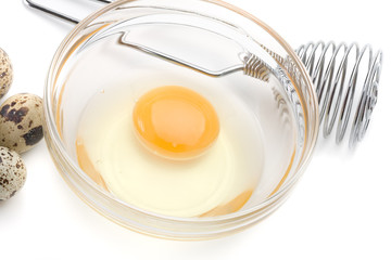 Dish of liquid egg, whisk and quail eggs