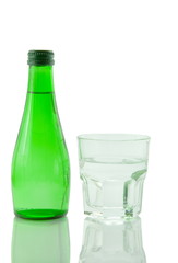 Bottle and glass of mineral water reflected on white background