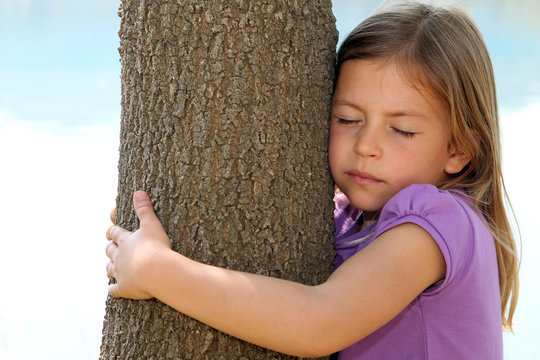 Cute young girl hugging a tree