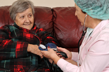 A nurse measuring senior patient's blood pressure.