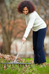 Redhead woman using a rake for cleaning