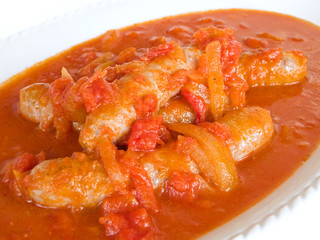 Sausages in tomato sauce on white dish.