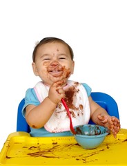 baby girl with messy face eating chocolate pudding