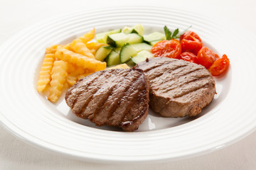 Grilled steaks with chips and vegetables
