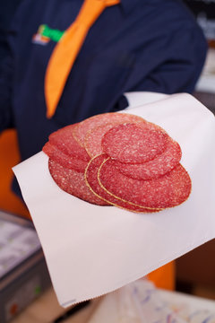 verkäuferin zeigt salami aufschnitt