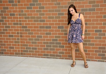 teen girl standing by a brick wall