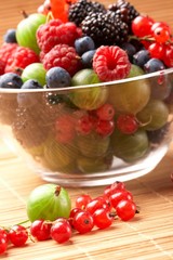 Fruit mix in the glass container, on a table from straw