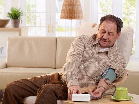 Old man measuring blood pressure at home