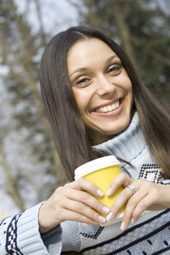Beautiful girl in a park drinking coffee