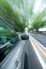 The car moves at great speed at the sunny day.