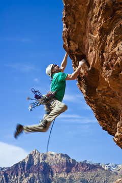 Male rock climber reaching for the summit.